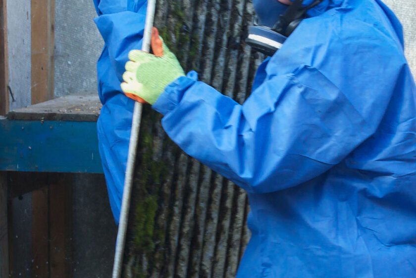 Man in protective mask and suit removing wall panel