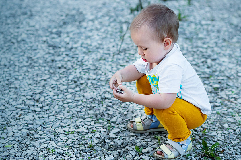 Small child picking up grey rocks