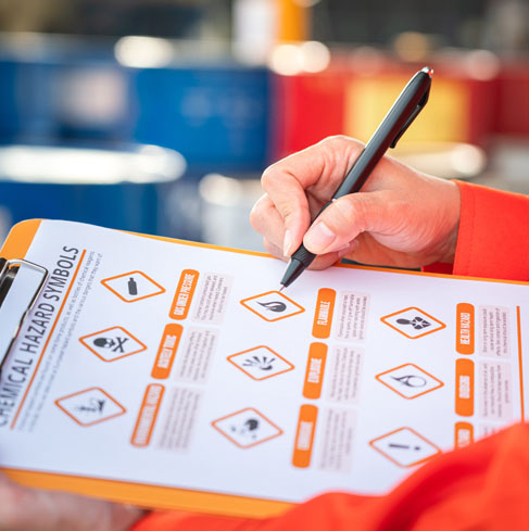 clipboard showing chemical hazard symbols